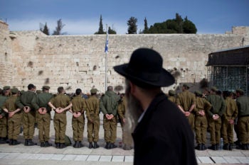 A haredi Orthodox man watching Israeli soldiers at an army ceremony at the Western Wall in Jerusalem, Feb. 22, 2012. (Yonatan Sindel/FLASH90/JTA)