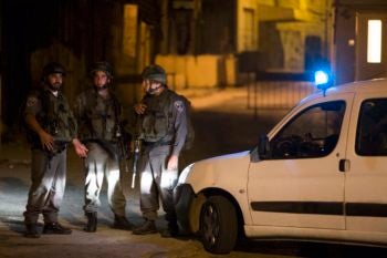 Israeli soldiers in Hebron stand near the scene where a fellow soldier was fatally shot by a sniper on Sept. 22, 2013. (Yonatan Sindel/Flash 90)