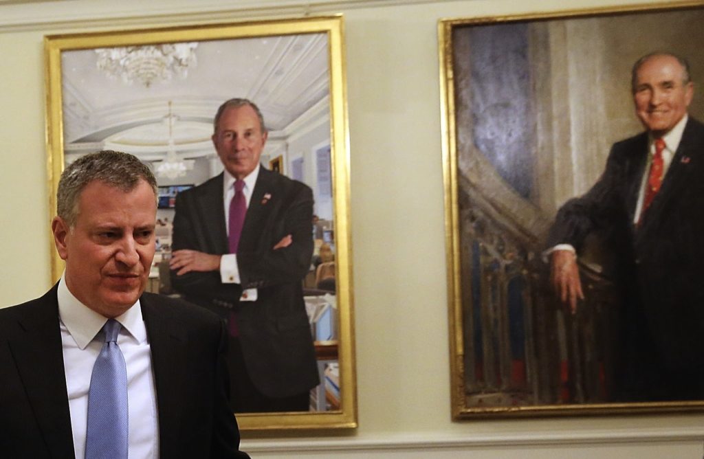 New York City Mayor Bill de Blasio, pictured here walking past portraits of his predecessors, said that defending Israel is part of his job description. (Spencer Platt/Getty Images)