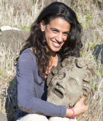 A member of the archaeological team holds the bronze mask of the god Pan, uncovered at the University of Haifa’s excavation at Hippos-Sussita. (University of Haifa)