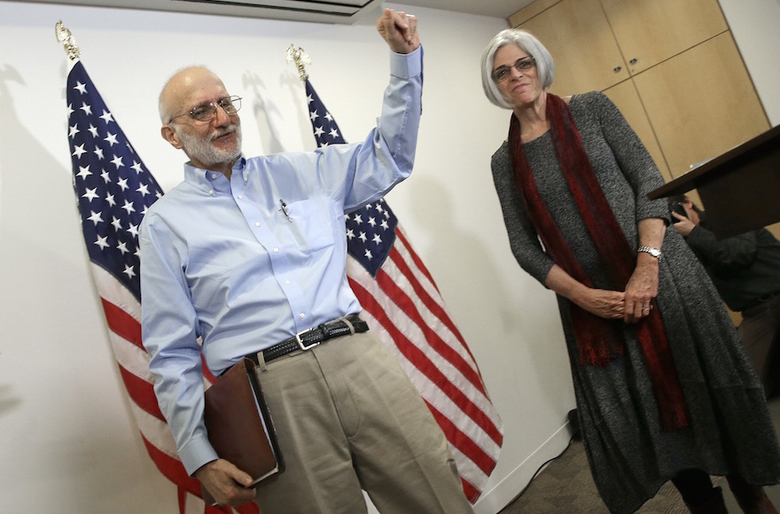 Alan Gross, freed from a Cuban prison earlier in the day, waves after concluding his remarks with his wife, Judy, at a news conference in Washington shortly after arriving in the United States, Dec. 17, 2014. (Win McNamee/Getty Images)