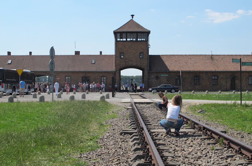 A woman takes a picture of a friend at the looming tower entrance to Birkenau in July 2015. (Ruth Ellen Gruber)
