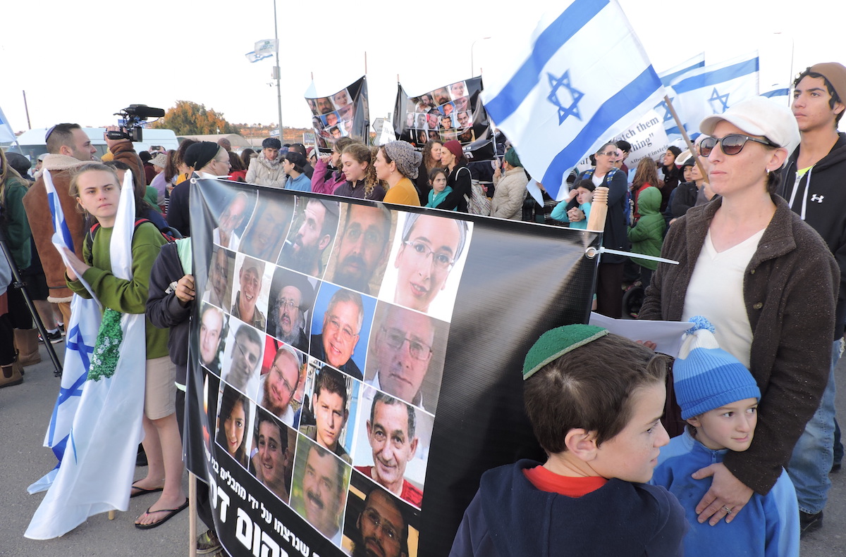 Protesters in Gush Etzion holding a poster of Israelis killed in terrorist attacks, Nov. 23, 2015. (Ben Sales)