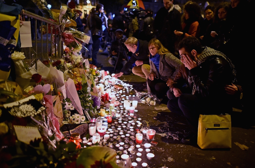 People placing flowers and candles on the pavement near the scene of Friday's Bataclan Theatre terrorist attack in Paris, Nov. 14, 2015. (Jeff Mitchell/Getty Images)