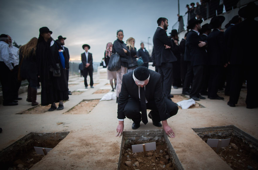 A mourner near the fresh graves of the seven children from the Sassoon family during their funeral in Jerusalem, March 23, 2015. (Yonatan Sindel/Flash90)