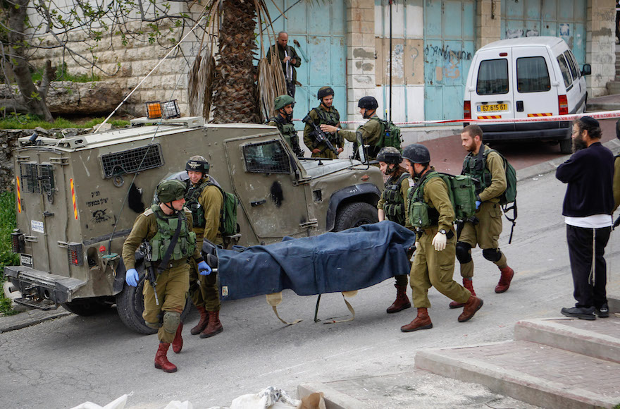 Israeli soldiers removing the body of a Palestinian man who stabbed a soldier in the West Bank city of Hebron, March 24, 2016. (Wissam Hashlamon/Flash90)