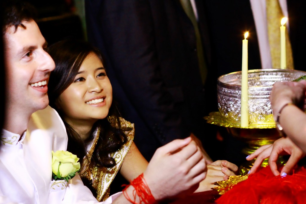 Family and friends tie red strings around the wrists of Rachel Sam and William Rubenstein in a Cambodian jong dai ceremony, Aug. 11, 2013. (Courtesy Rachel Sam and William Rubenstein)