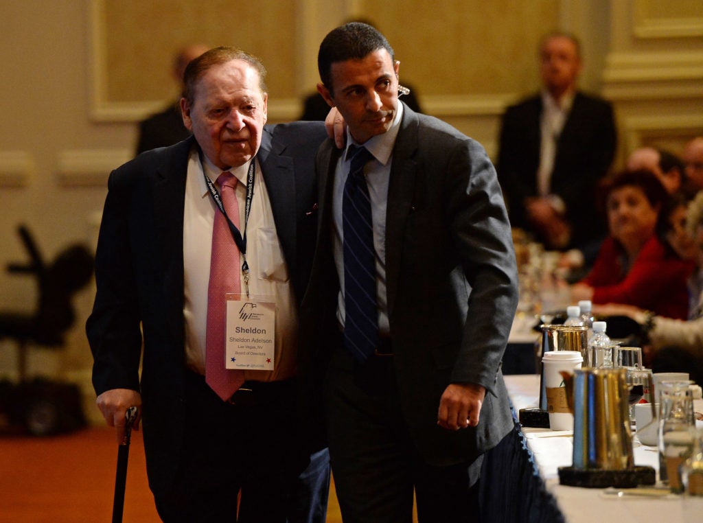 Sheldon Adelson (L) is escorted to his seat to listen to New Jersey Gov. Chris Christie speak during the Republican Jewish Coalition spring leadership meeting in Las Vegas. (Ethan Miller/Getty Images)