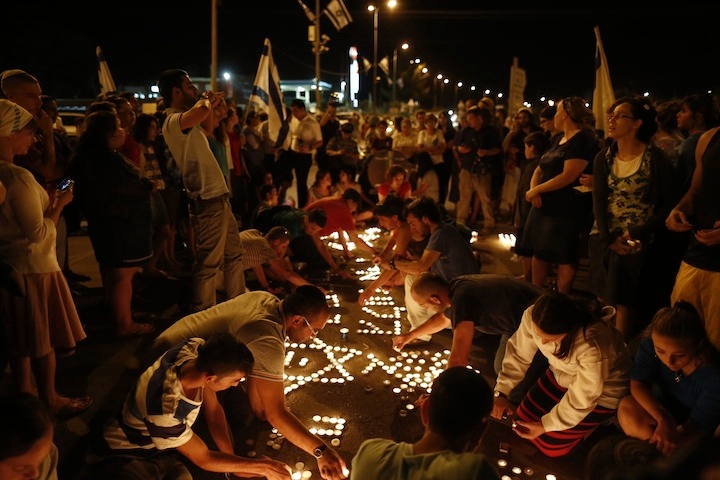 At the hitchhiking spot in the West Bank where three teenagers -- Eyal Yifrach, Naftali Fraenkel and Gilad Sha'ar -- were abducted, Israelis light memorial candles after the discovery of their bodies, June 30, 2014. (Yonatan Sindel/Flash 90)