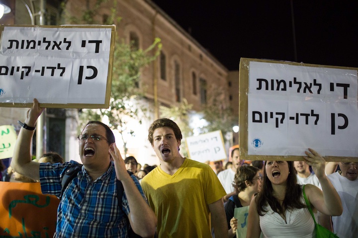 Participants in an anti-racism rally in Jerusalem holding signs that say,