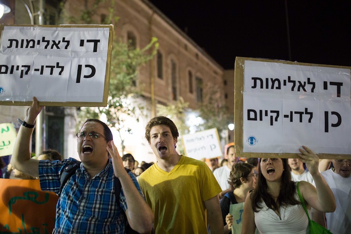 Participants in an anti-racism rally in Jerusalem holding signs that say, 