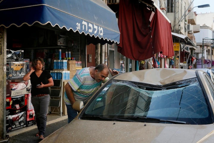 Israelis looking on at the site where remains of one of the rockets fired from Gaza into Israel that was intercepted by the Iron Dome fell in South Tel Aviv. July 10, 2014. (Miriam Alster/FLASH90)