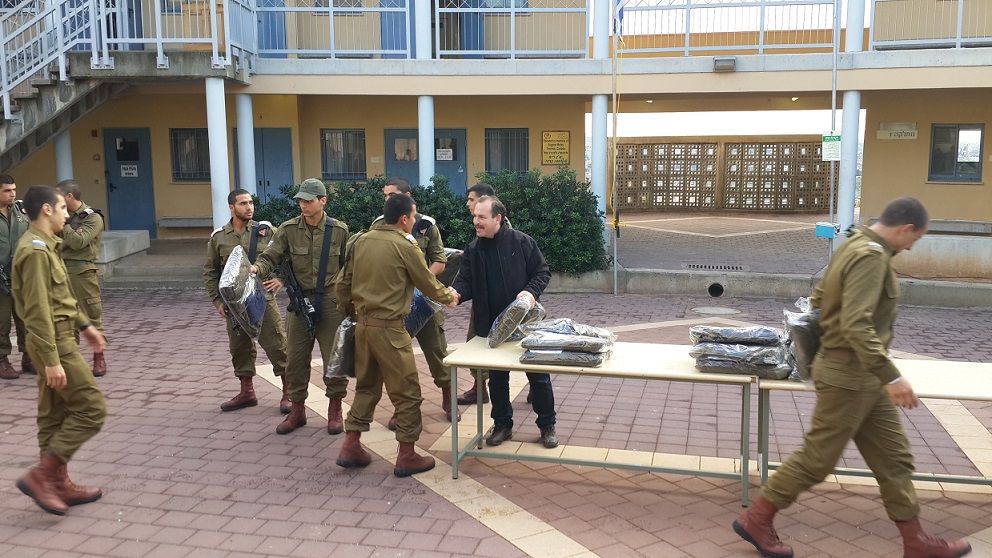 Yashar Lachayal's Leon Blankrot, in black, hands out aid packages containing fleece jackets, thermal shirts, gloves, hats and neck warmers to an all-Druze unit in the Israel Defense Forces, Nov. 28, 2014. (Courtesy Yashar Lachayal)