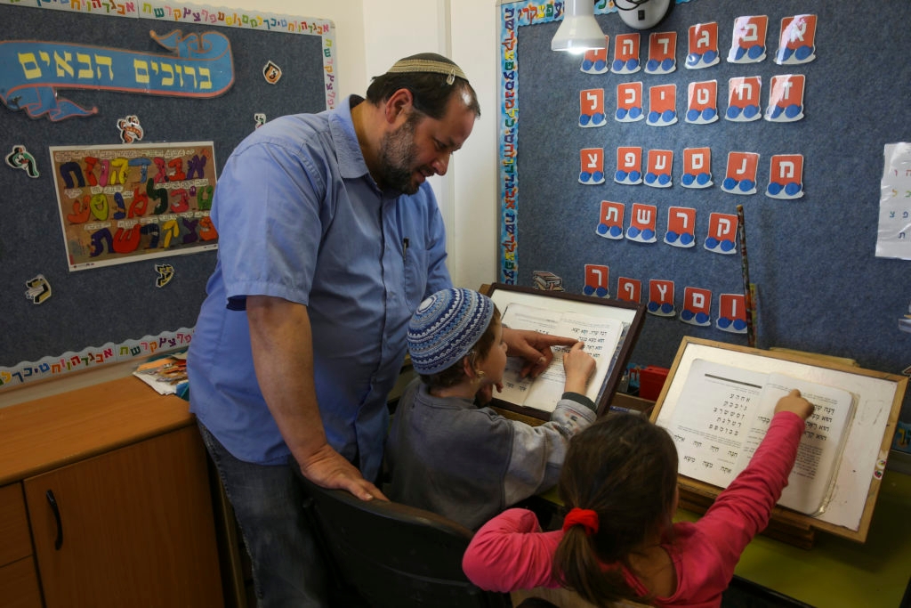 Knitted yarmulkes and pro-settler policies are not the face of religious Zionism after all? Here, Rabbi Eran Fletzki teaches children at a school in the West Bank settlement of Neve Daniel, Nov. 25, 2013. (Nati Shohat/Flash90)