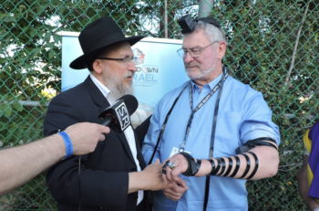 A rabbi places tefillin on Ron Mix, a Jewish retired offensive tackle who played for the San Diego Chargers and Oakland Raiders. (Ben Sales)