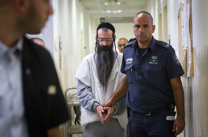 Yishai Schlissel is escorted by police after his hearing at the Jerusalem Magistrates Court on August 11, 2015. (Miriam Alster/Flash90)