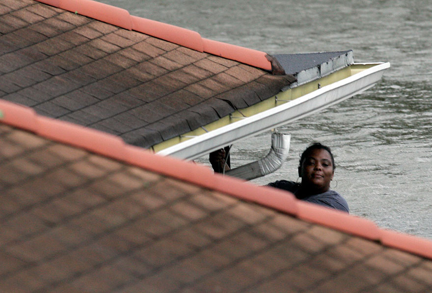 A woman hangs from her roof waiting to be rescued by New Orleans Fire Department workers after Hurricane Katrina came through on August 29, 2005 in New Orleans. (Chris Graythen/Getty Images)