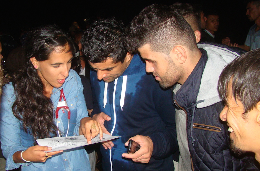 Israeli Doctor Tali Shaltiel explains to a group of Afghans how to get to the refugee registration center some 40 miles away. (Gavin Rabinowitz)