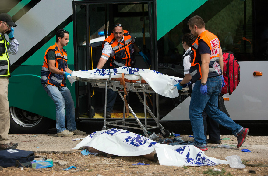 Rescue personnel working near a victim of a terror attack in the East Talpiot neighborhood of Jerusalem, in which two people were killed and more than a dozen wounded on a city bus by two assailants armed with a gun and a knife. (Yonatan Sindel/FLASH90)