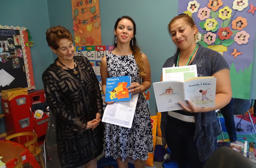 From left: Linda Frank, chair of HIPPY USA's trustees, and home visitors Sonia Sorto and Idis Argueta displaying some of the books and matching curricula given free to families in the HIPPY program. (Suzanne Pollak)