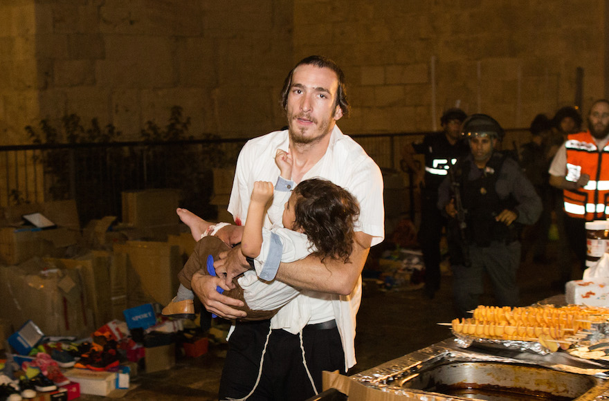 A Jewish man carrying a baby injured in a stabbing attack in the Old City of Jerusalem on October 3, 2015. (Yonatan Sindel/Flash90)