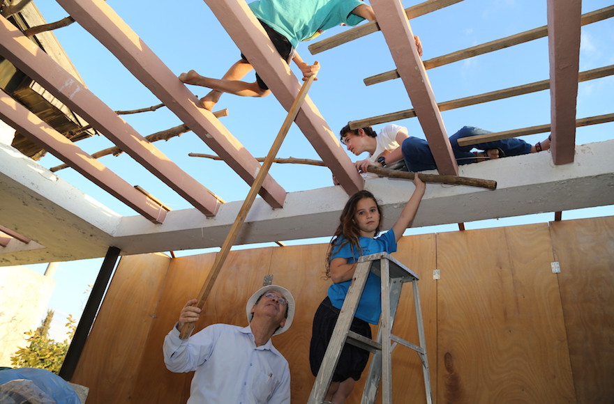 Children building a sukkah on Oct. 1, 2014. (Gershon Elinson/Flash90)