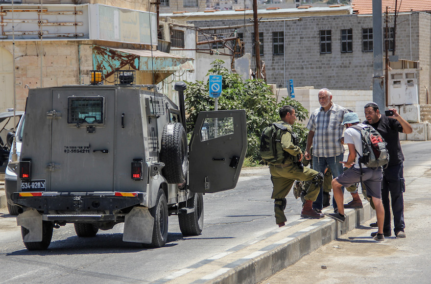 Israeli settlers recording a video and arguing with a member of Breaking the Silence group in the West Bank city of Hebron, July 10, 2015. (Garrett Mills/Flash90) 