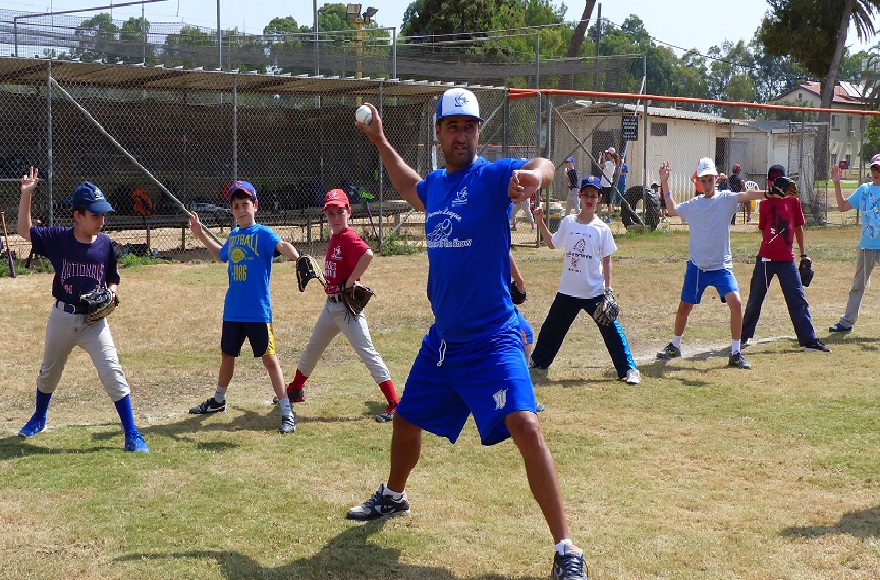 Nate Fish, director of the Israel Association of Baseball, demonstrating pitching to Israeli kids. (Margo Sugarman/IAB)