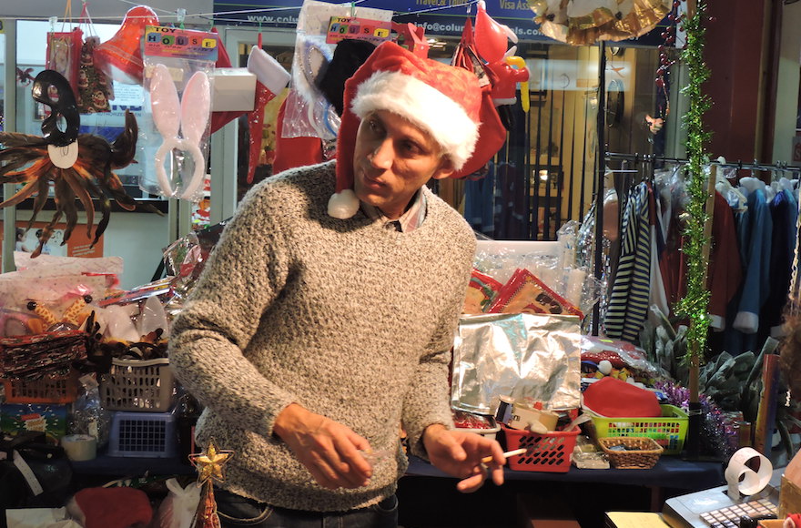 Alex, a cashier at the Novy God Market in Tel Aviv's Central Bus Station, sells Christmas and New years' kitsch to thousands of mostly Russian-speaking customers each December. (Ben Sales)