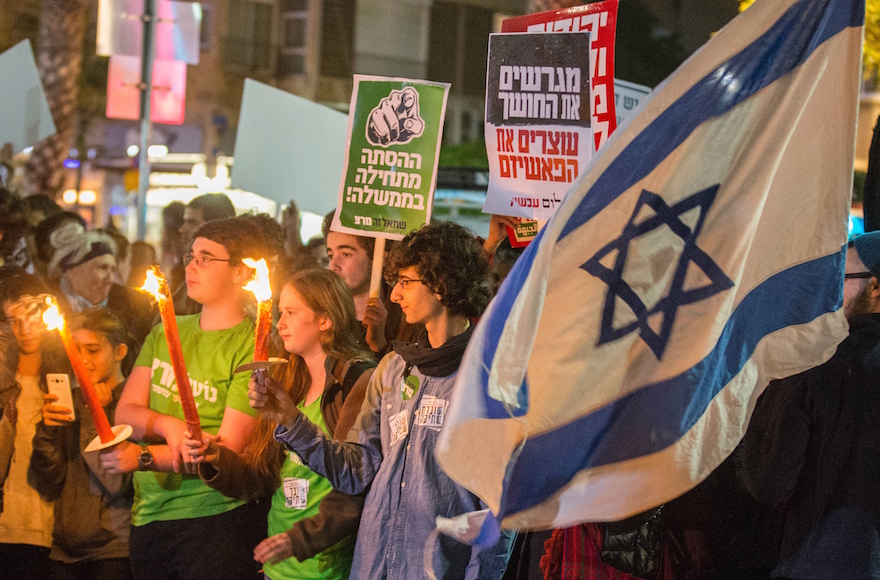 Israeli left-wing activists holding placards and their national flag during a Peace Now march calling on Israelis to end the occupation of Palestinian lands, in Tel Aviv, Dec. 19, 2015. (Jack Guez/AFP/Getty Images)