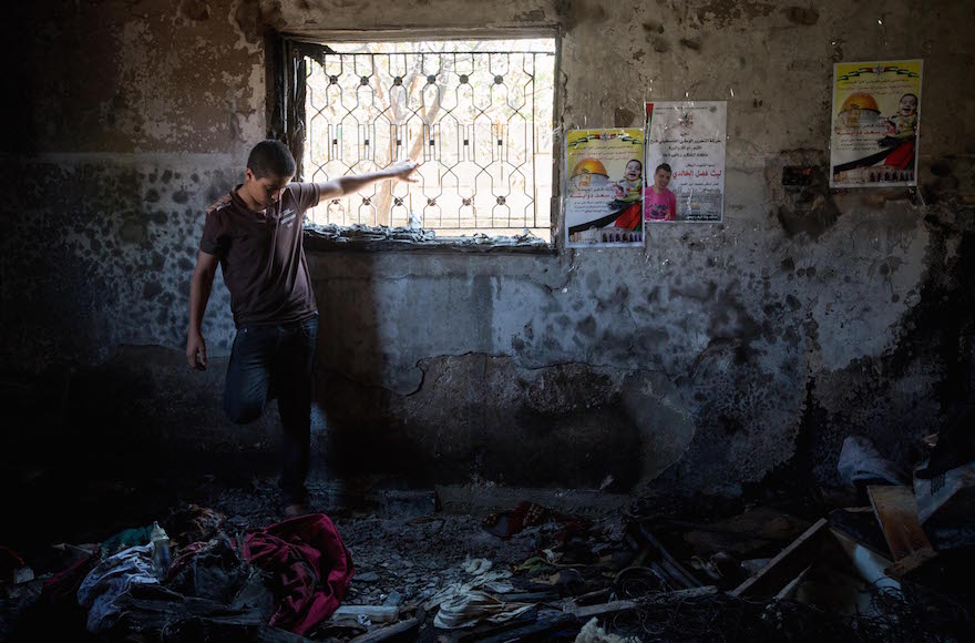 A Palestinian boy surveying the damage at a home in the West Bank village of Duma burned by Jewish extremists, August 6, 2015. (Miriam Alster/Flash90)
