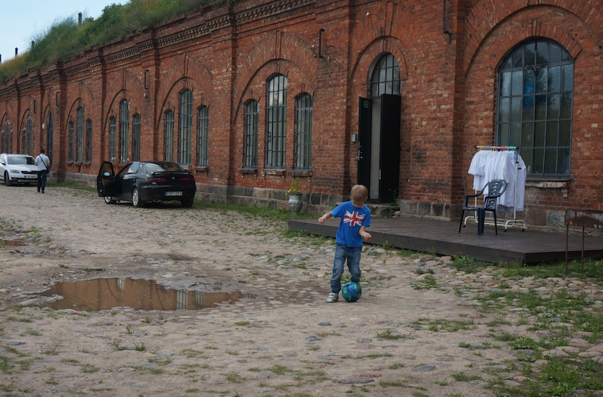 A boy playing soccer at the entrance to the former concentration camp known as the Seventh Fort in Kaunas, Lithuania, on July 12, 2016. (JTA/Cnaan Liphshiz) 