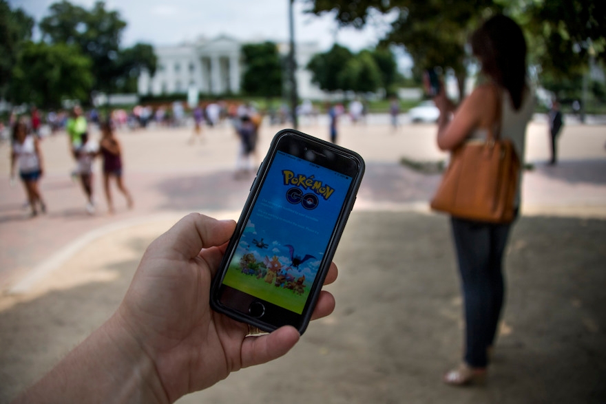 A man holds up his cell phone with a screen shot of the Pokemon Go game as a woman searches on her cell phone for a Pokemon in front of the White House in Washington, DC, July 12, 2016. ( Jim Watson /AFP/Getty Images)