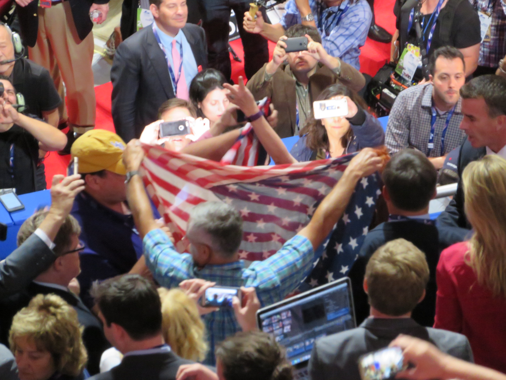 A Code Pink protester pokes a victory sign threw a shroud of American flags created by angered delegates at the Republican National Convention in Cleveland on July 19, 2016. (Ron Kampeas)