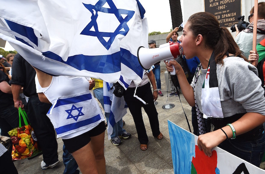 A protestor speaking into a megaphone as pro-Israeli counter protesters wave Israeli flags during a demonstration against Israel's military operations in the Gaza Strip, in Los Angeles, California, Aug. 2, 2014 (Robyn Beck/AFP/Getty Images) 