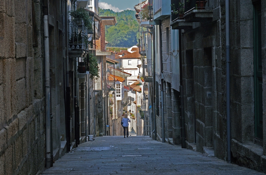 A tourist walking down the historic Jewish Quarter of the town of Ribadavia in Spain, Sept. 26, 2016. (Cnaan Liphshiz)