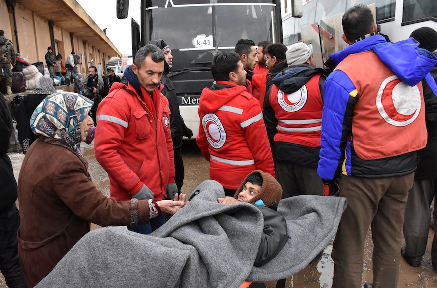 A Syrian civilian being loaded into a bus by members of the Syrian Arab Red Crescent at a makeshift shelter in Jibrin on the eastern outskirts of Aleppo, Dec. 22, 2016. (George Ourfalian/AFP/Getty Images)