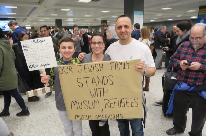Jacob, left, Miri and Tal Zlotnitsky holding up a poster welcoming Muslim arrivals at Dulles International Airport in Virginia, Jan. 28 2017. (Ron Kampeas)