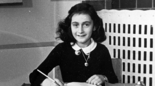 Anne Frank holding a pen in a black-and-white image