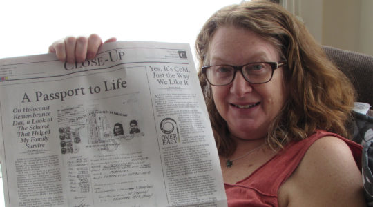Heidi Fishman holding up an op-ed she wrote about her family's rescue from the Holocaust using a Paraguayan passport. Courtesy of Heidi Fishman