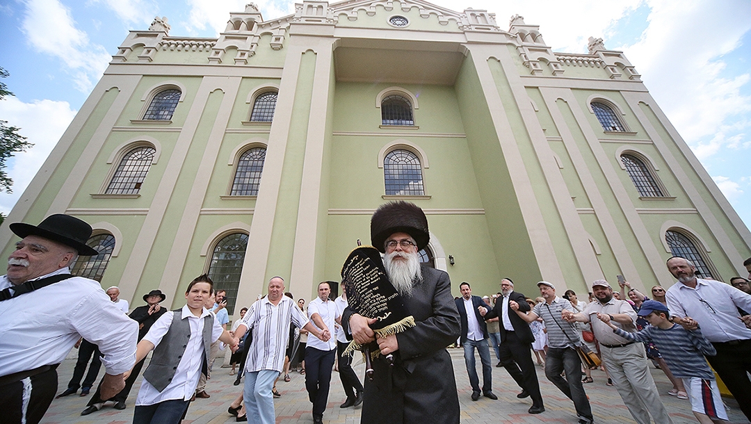 Yaakov Dov Bleich carrying a Torah scroll into the synagogue of Drohobycz, Ukraine on July 3, 2019. (Rephael Isaak Vilenskiy)