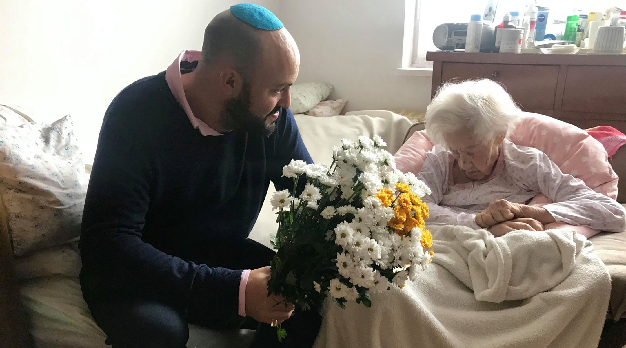 Krystyna Danko receiving flowers from Jonny Daniels on in her apartment in Warsaw, Poland on her 102nd birthday on July 9, 2019. (From the Depths)