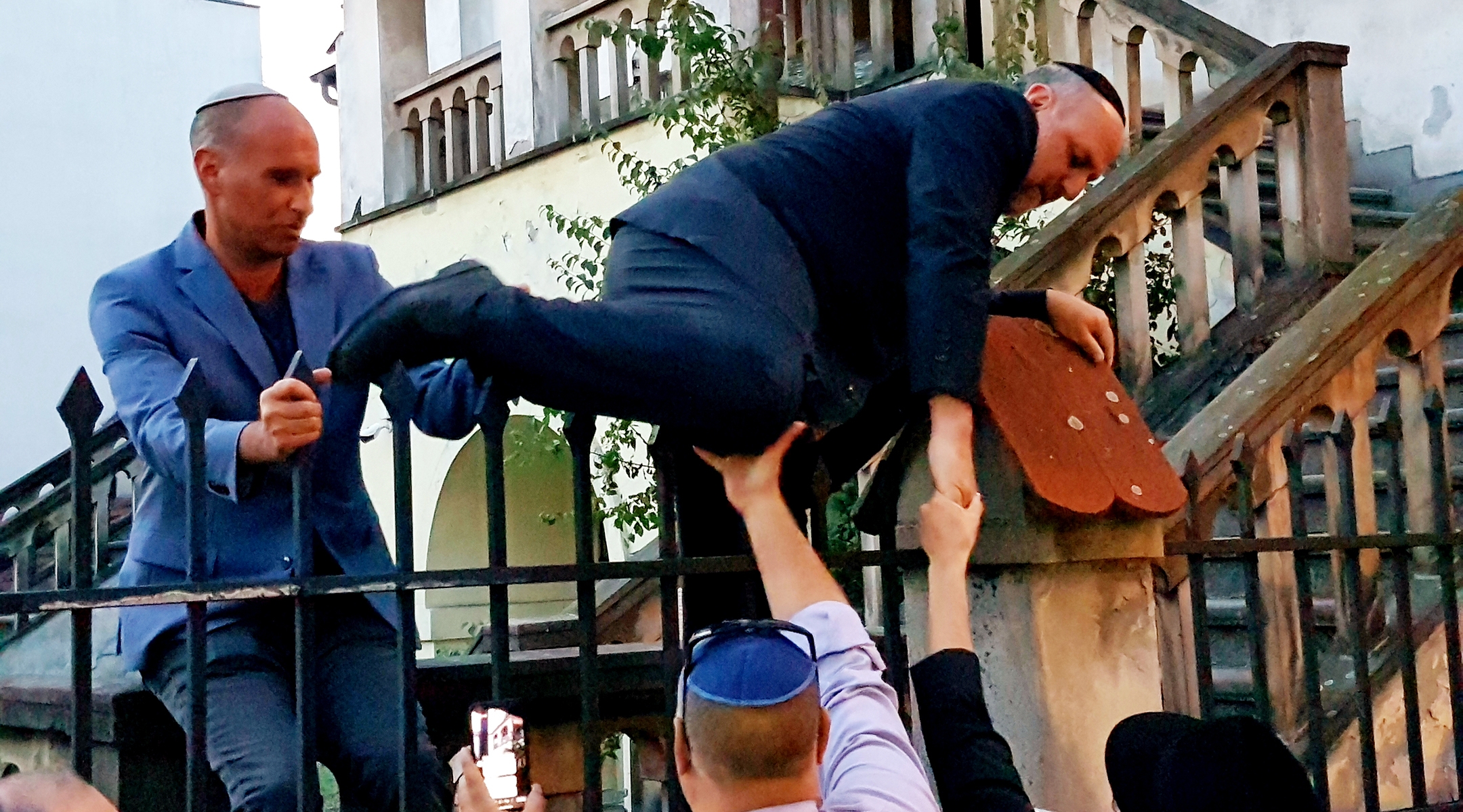 Le rabbin Michael Schudrich escalade la clôture de la synagogue Izaak barricadée à Cracovie, en Pologne, le 4 juillet 2019. (Shimon Briman)