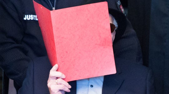 Bruno Dey, who is accused of being accessory to murder at a Nazi concentration camp, covering his face as he arrives in a courtroom in Hamburg, Germany on October 17, 2019.(Daniel Bockwoldt / POOL / AFP via Getty Images)