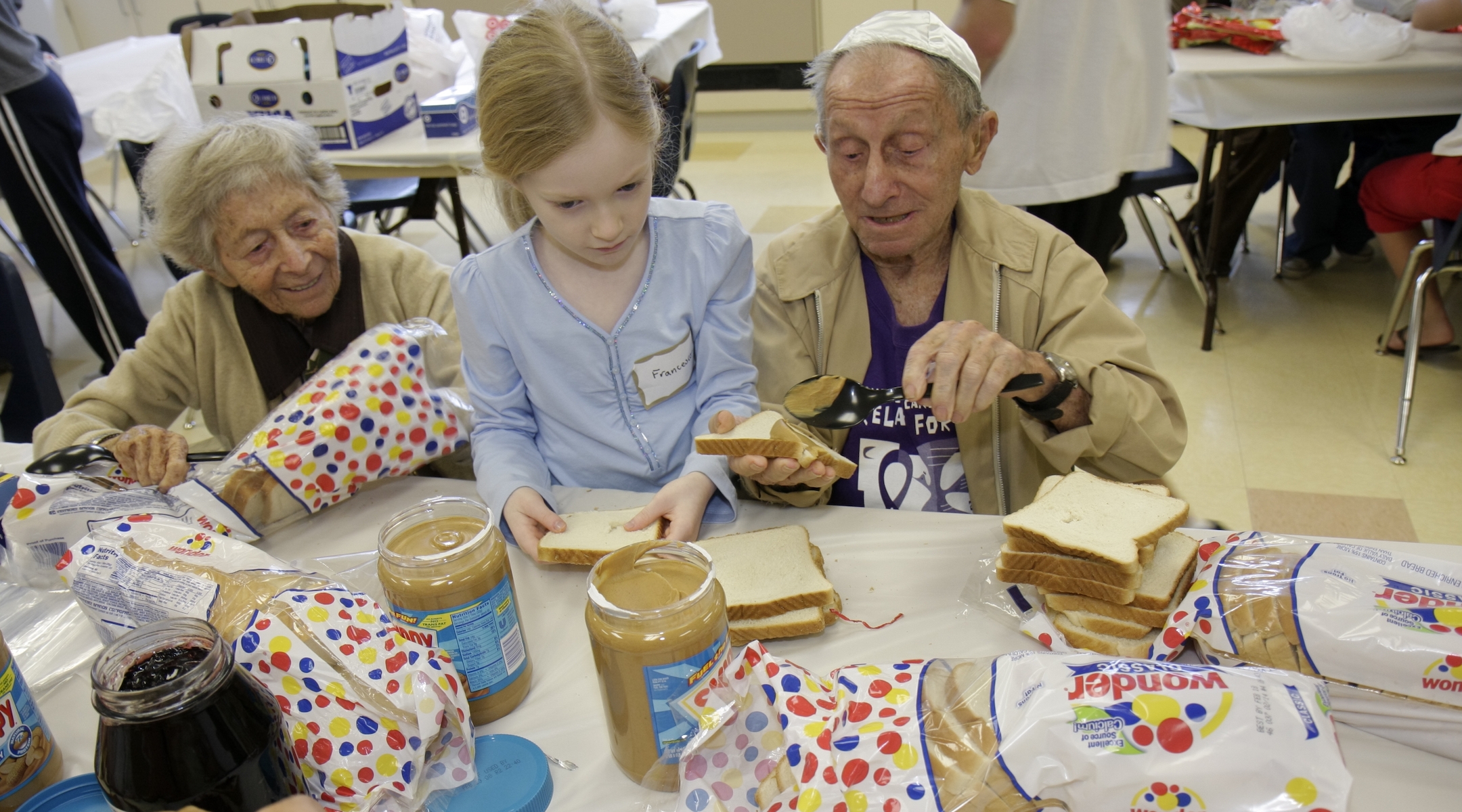 A senior couple and young girl preparing food for the Mitzvah Weekend at a synagogue in 2008. (Jeffrey Greenberg/Getty Images)