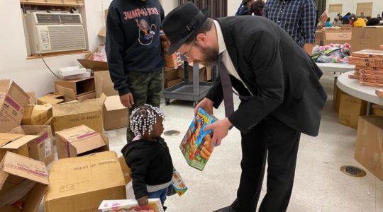 Rabbi Moshe Z. Schapiro shows a toy to a child during the charity drive in Jersey City on December 23, 2019. (Courtesy of Benny Polatseck)