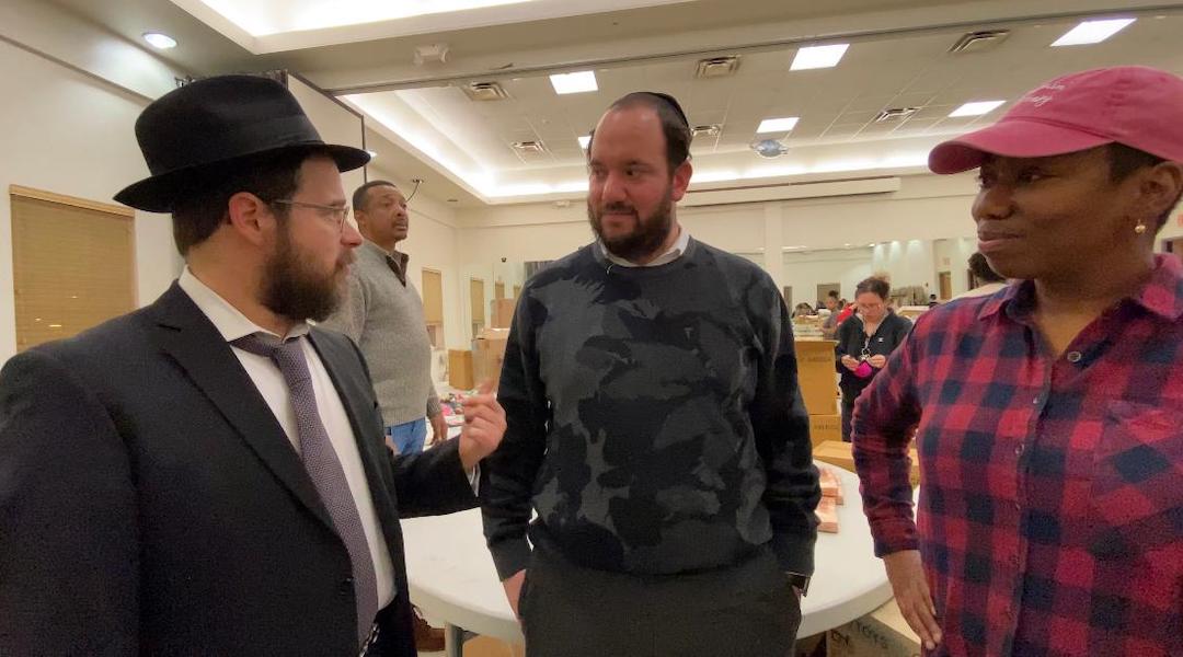 From left: Rabbi Moshe Z. Schapiro, Chesky Deutsch and Pam Johnson talk during the charity drive. (Courtesy of Benny Polatseck)