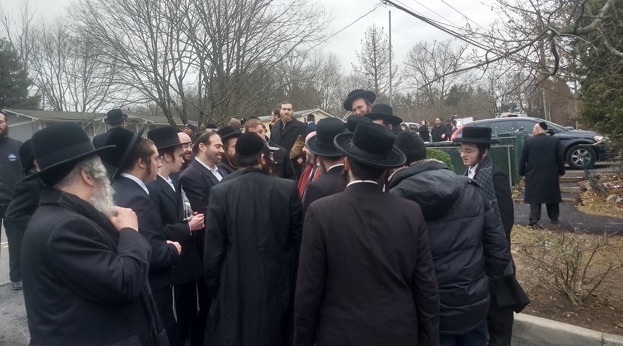 A crowd of Orthodox Jews gathers Sunday outside the house where the stabbing took place. (Ben Sales)