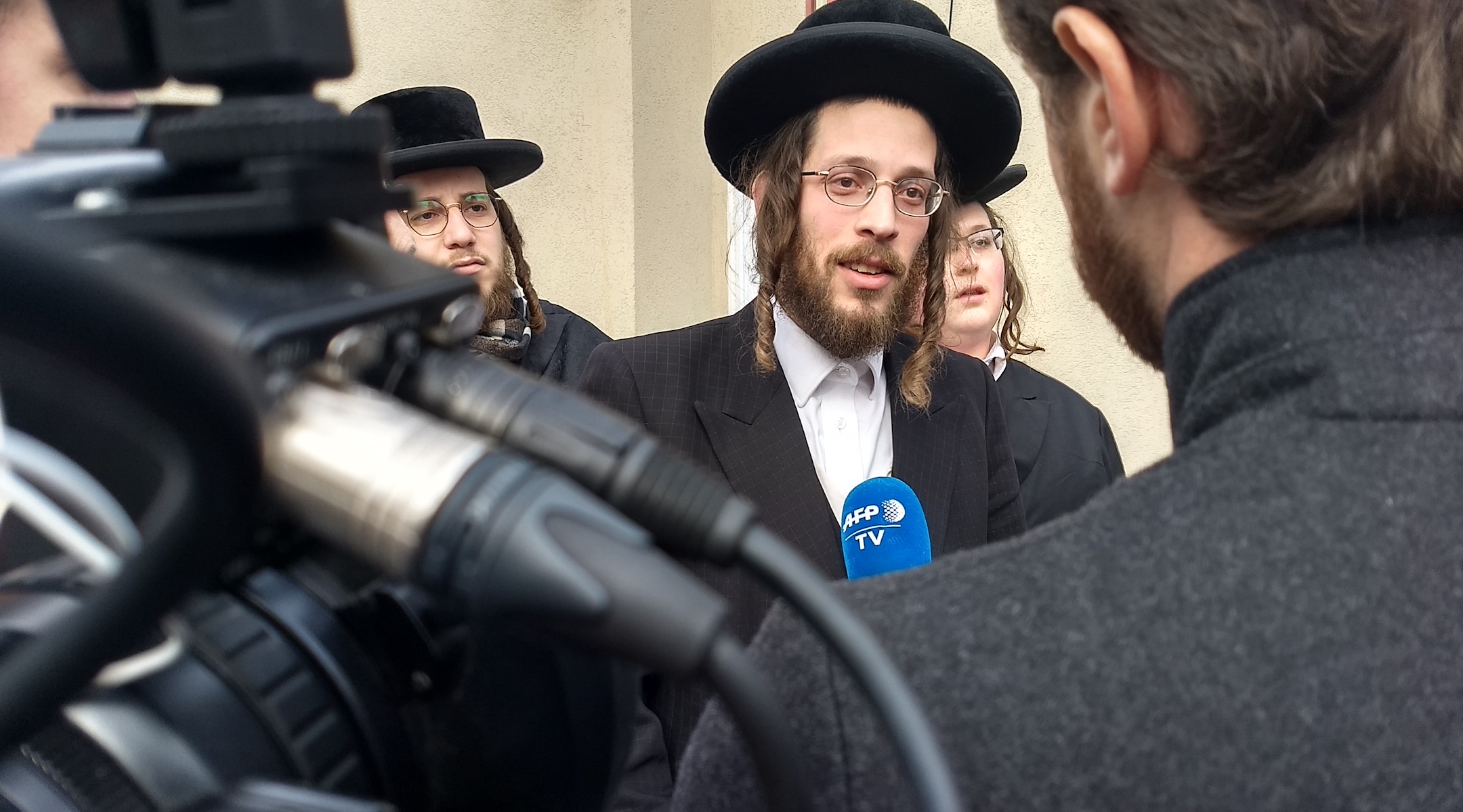 Joseph Gluck, who threw a coffee table at the attacker's head Saturday night, speaks to reporters the next day outside the rabbi's house. (Ben Sales)