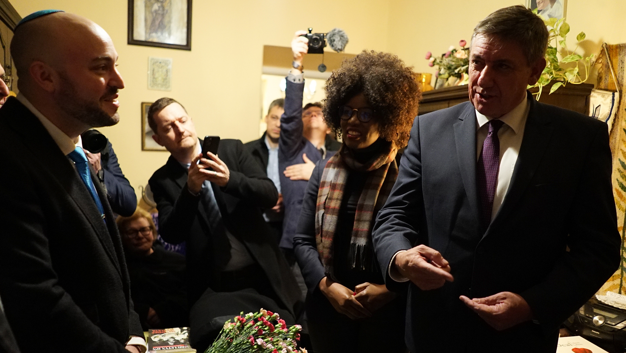 Flemish Prime Minister Jan Jambon, right, Froum the Depths founder Jonny Daniels, left, and members of the Belgian delegation visiting the home of Maria Nowak in Krakow, Poland on Jan. 20, 2020. (Tytus Kondracki)